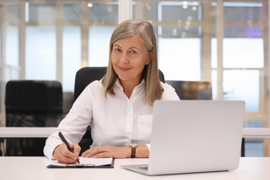 Confident woman with clipboard and laptop working in office. Lawyer, businesswoman, accountant or manager