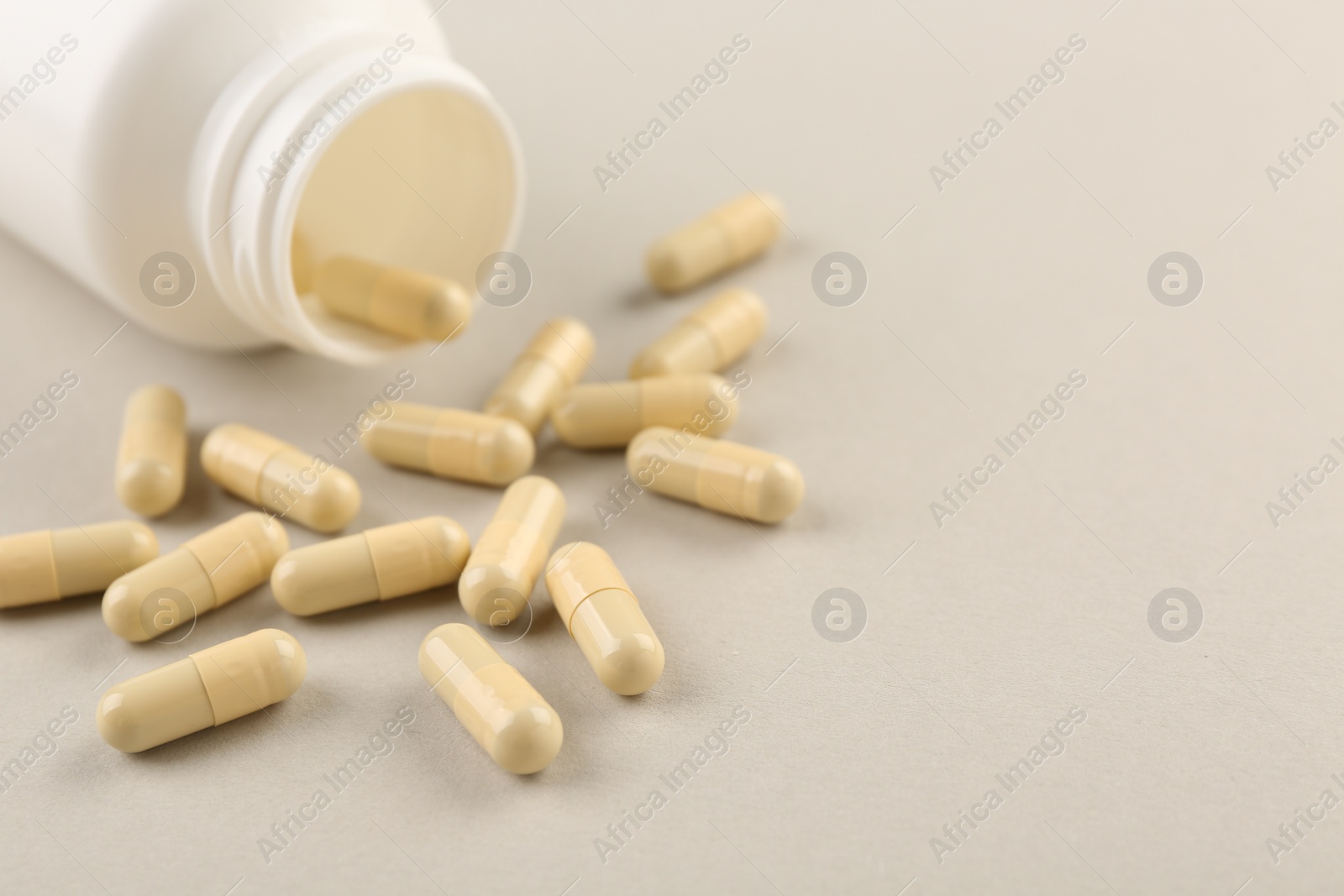 Photo of Bottle and vitamin capsules on light background, closeup. Space for text