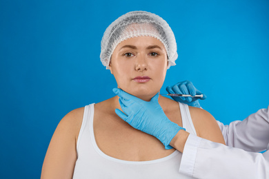 Photo of Woman with double chin getting injection on blue background. Cosmetic surgery