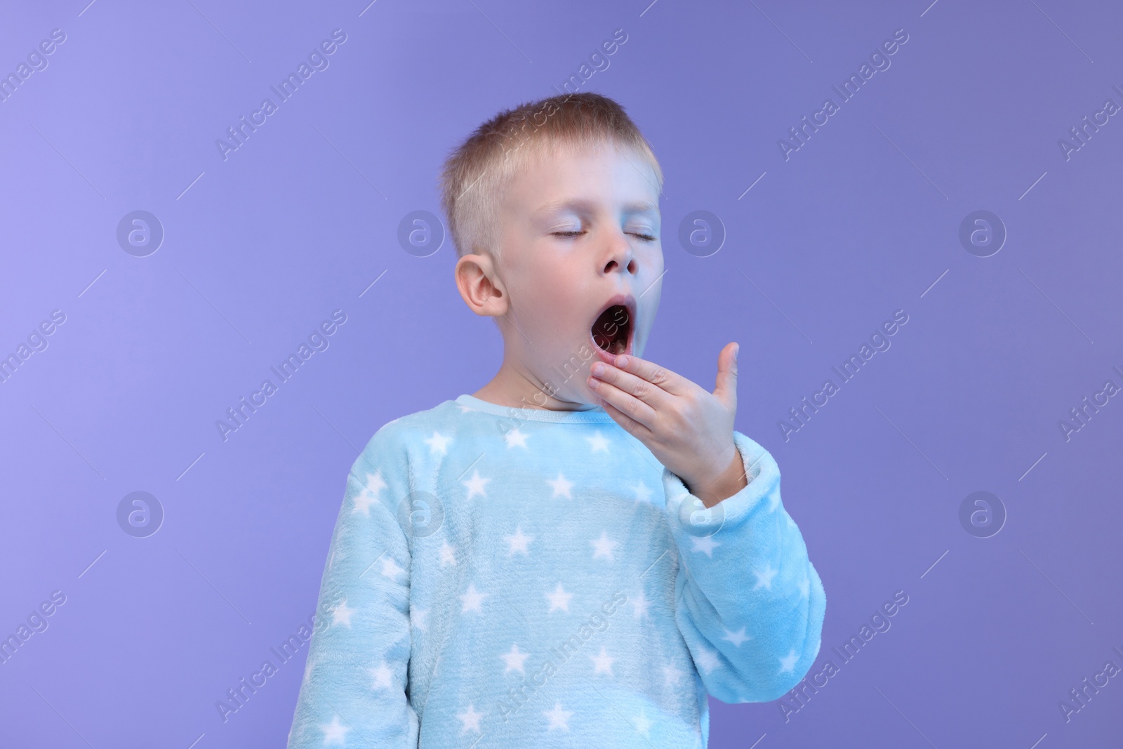 Photo of Sleepy boy yawning on purple background. Insomnia problem