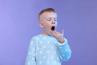 Photo of Sleepy boy yawning on purple background. Insomnia problem