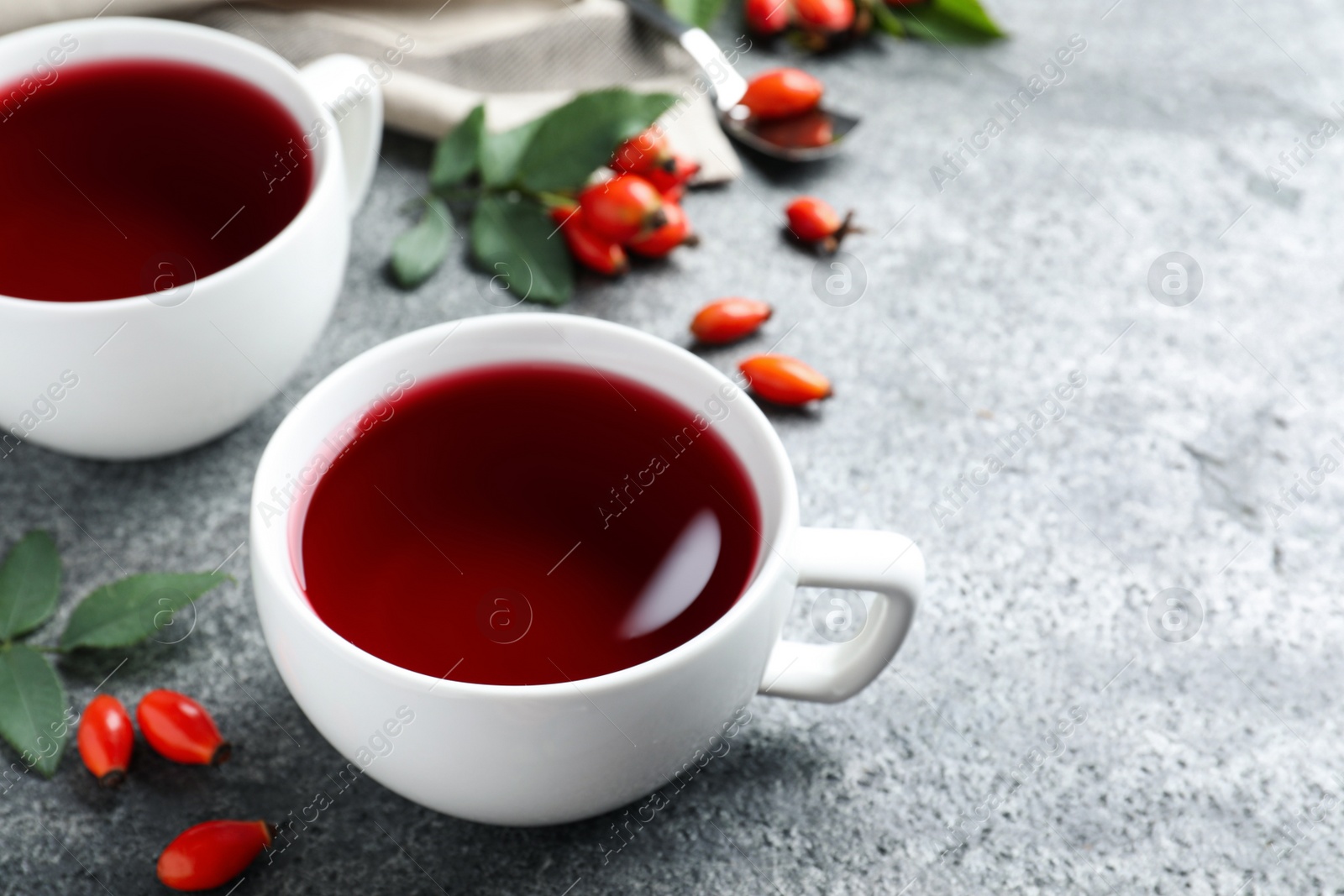 Photo of Fresh rose hip tea and berries on grey table, closeup. Space for text