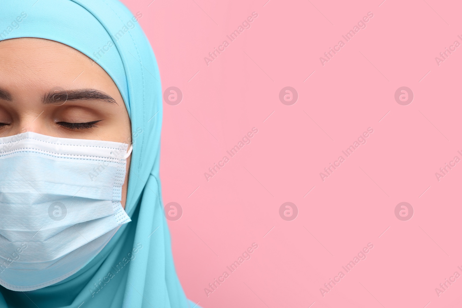 Photo of Muslim woman in hijab and medical mask on pink background, closeup. Space for text