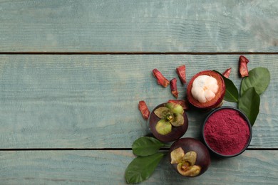 Purple mangosteen powder and fruits on light blue wooden table, flat lay. Space for text