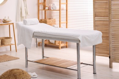 Comfortable massage table with clean towels in spa center