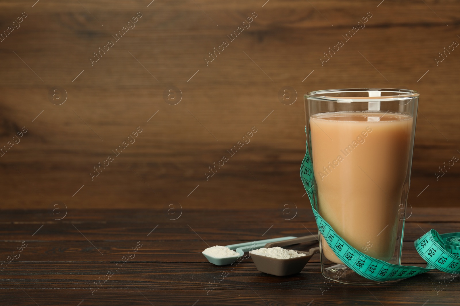 Photo of Tasty shake, measuring tape and powder on wooden table, space for text. Weight loss