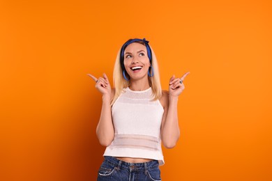 Photo of Smiling hippie woman pointing at something on orange background