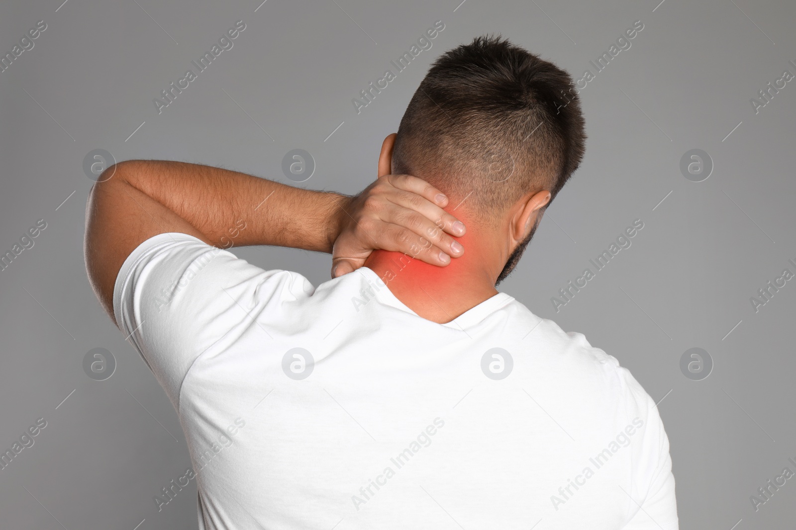 Image of Man suffering from neck pain on grey background, back view