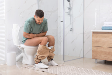 Photo of Man suffering from hemorrhoid on toilet bowl in rest room