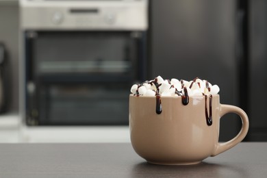 Photo of Cup of delicious drink with marshmallows and chocolate on grey table in kitchen. Space for text