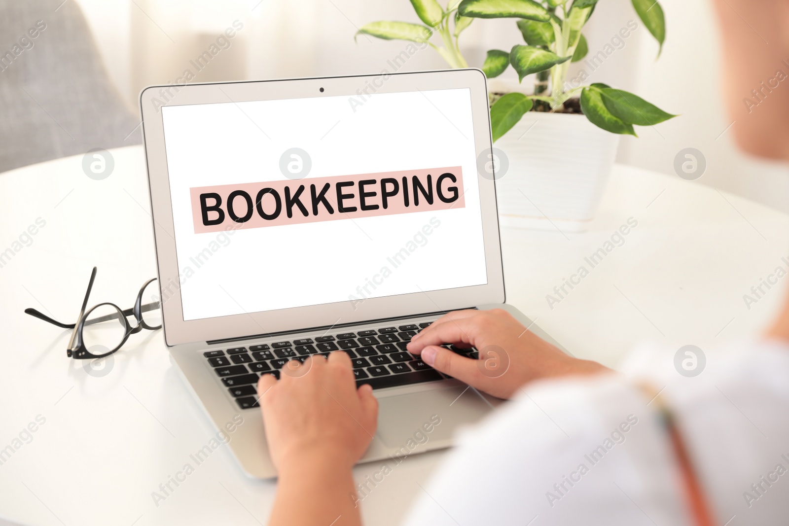 Image of Bookkeeping concept. Woman working with laptop at white table, closeup