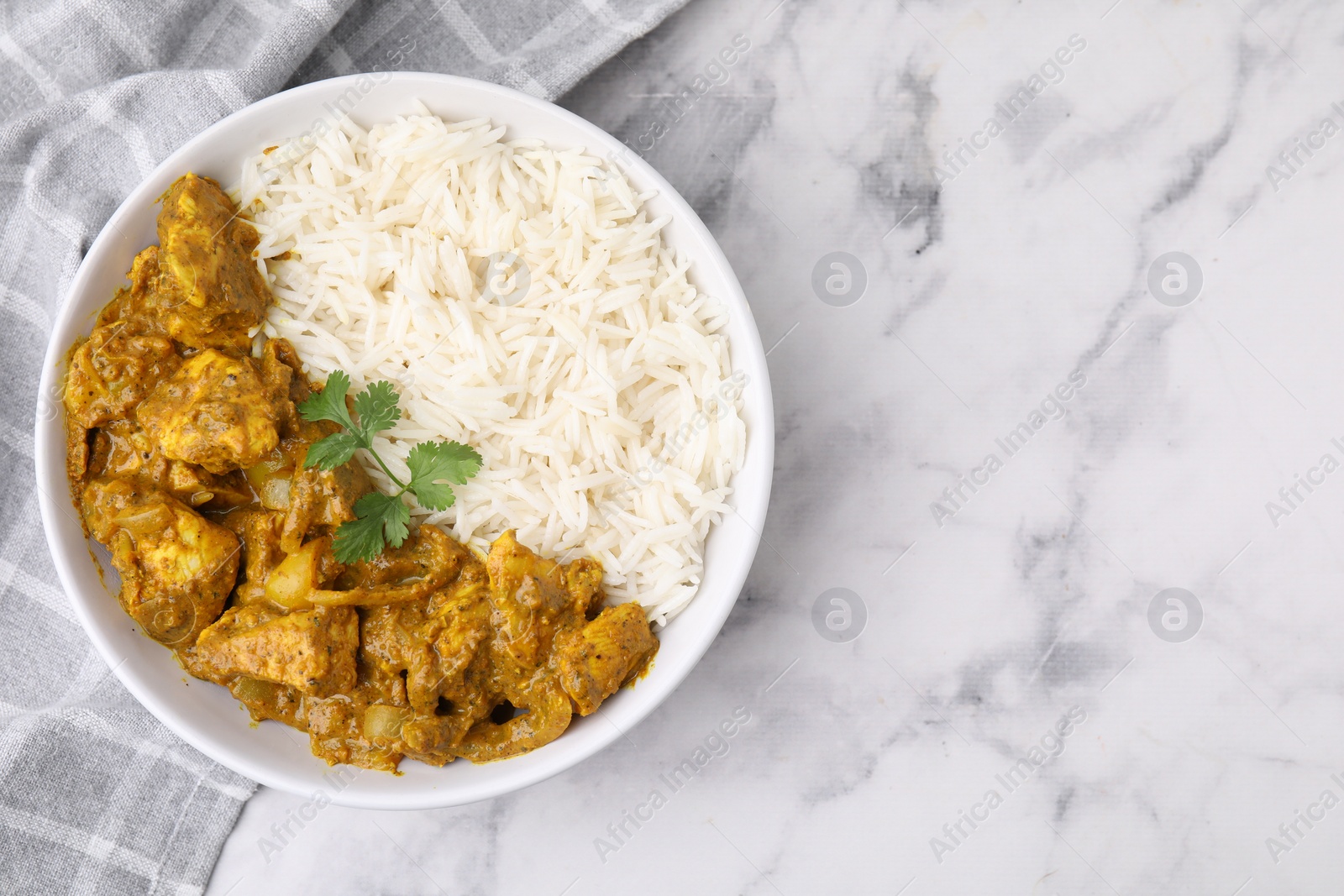 Photo of Delicious chicken curry with rice on white marble table, top view. Space for text