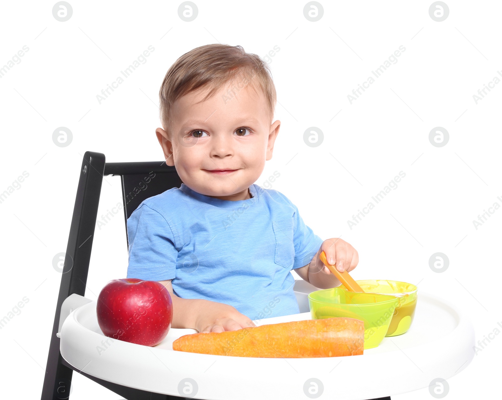 Photo of Adorable little child having breakfast in highchair against white background. Healthy baby food