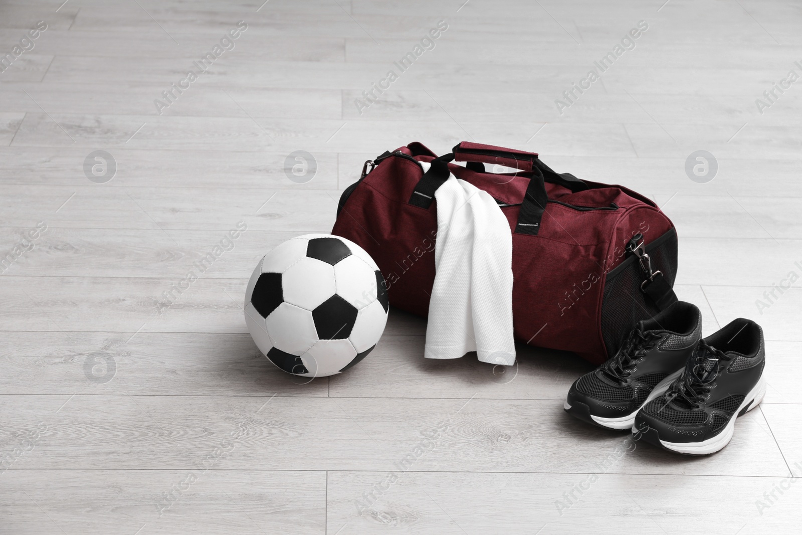 Photo of Sports bag with training stuff and equipment on white floor