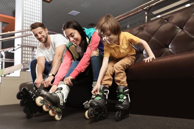 Photo of Happy family putting on roller skates indoors