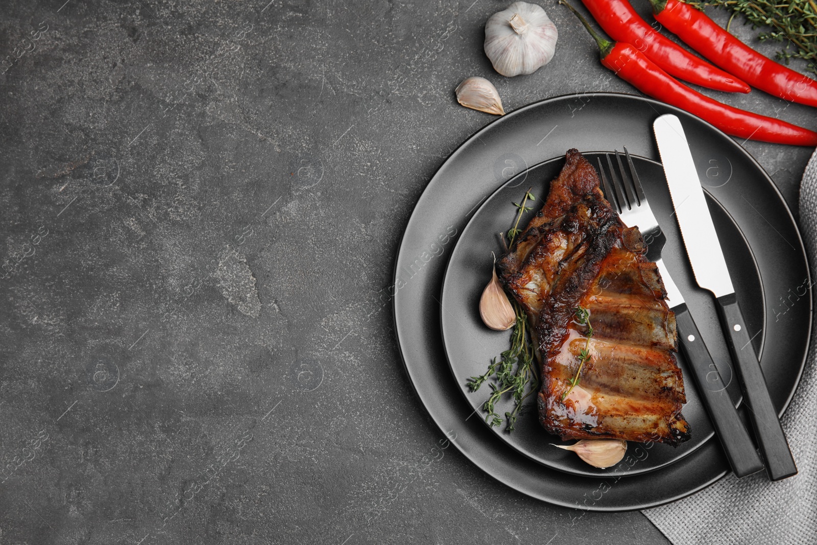 Photo of Tasty grilled ribs served on grey table, flat lay. Space for text