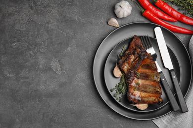 Photo of Tasty grilled ribs served on grey table, flat lay. Space for text