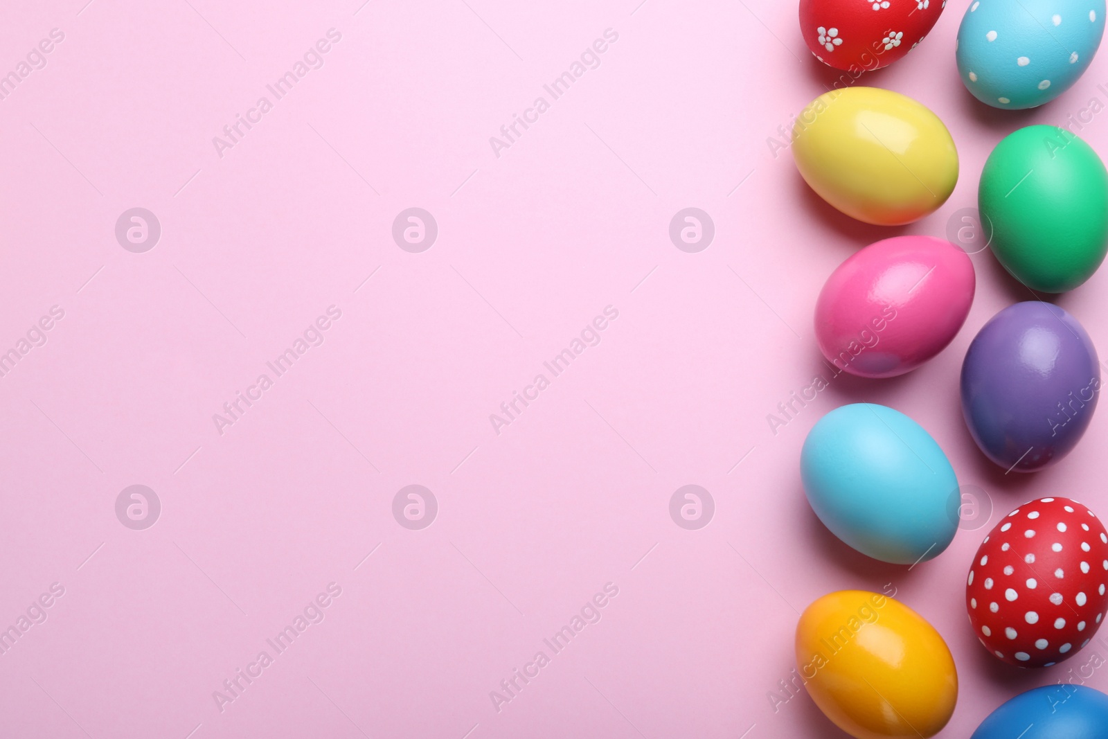 Photo of Bright painted eggs on pink background, flat lay with space for text. Happy Easter