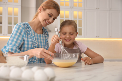 Photo of Mother and daughter making dough together in kitchen