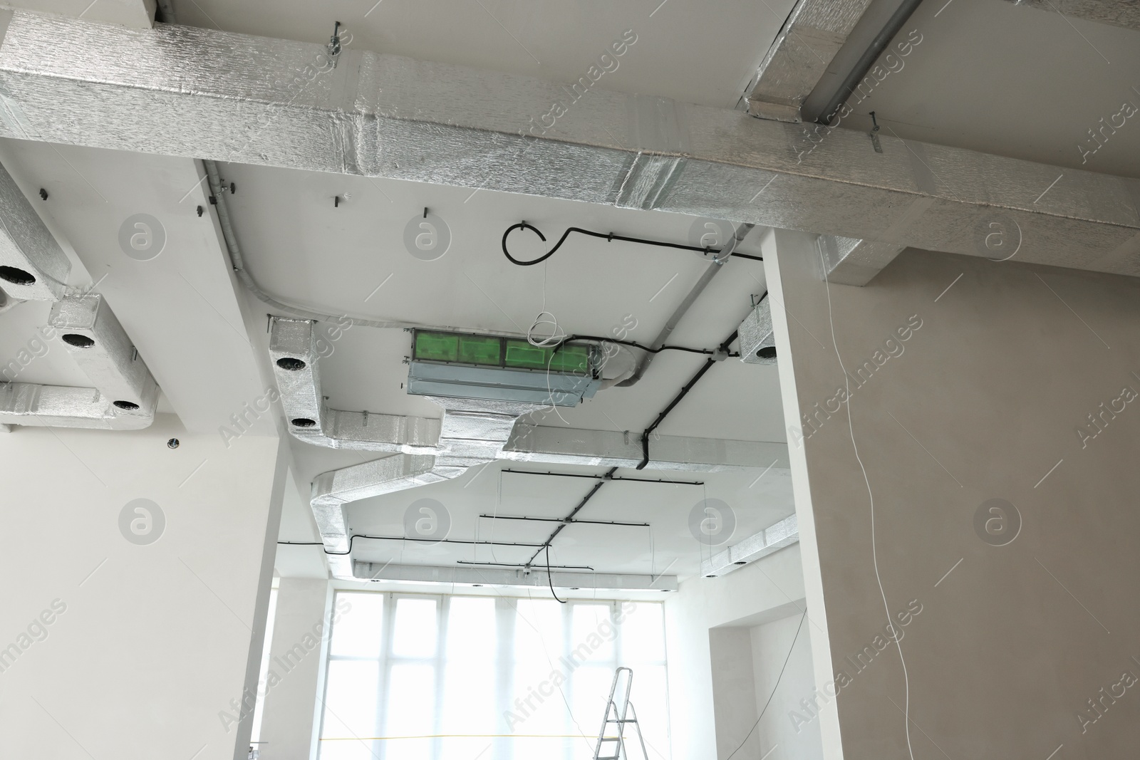 Photo of Ventilation system and wires on white ceiling indoors