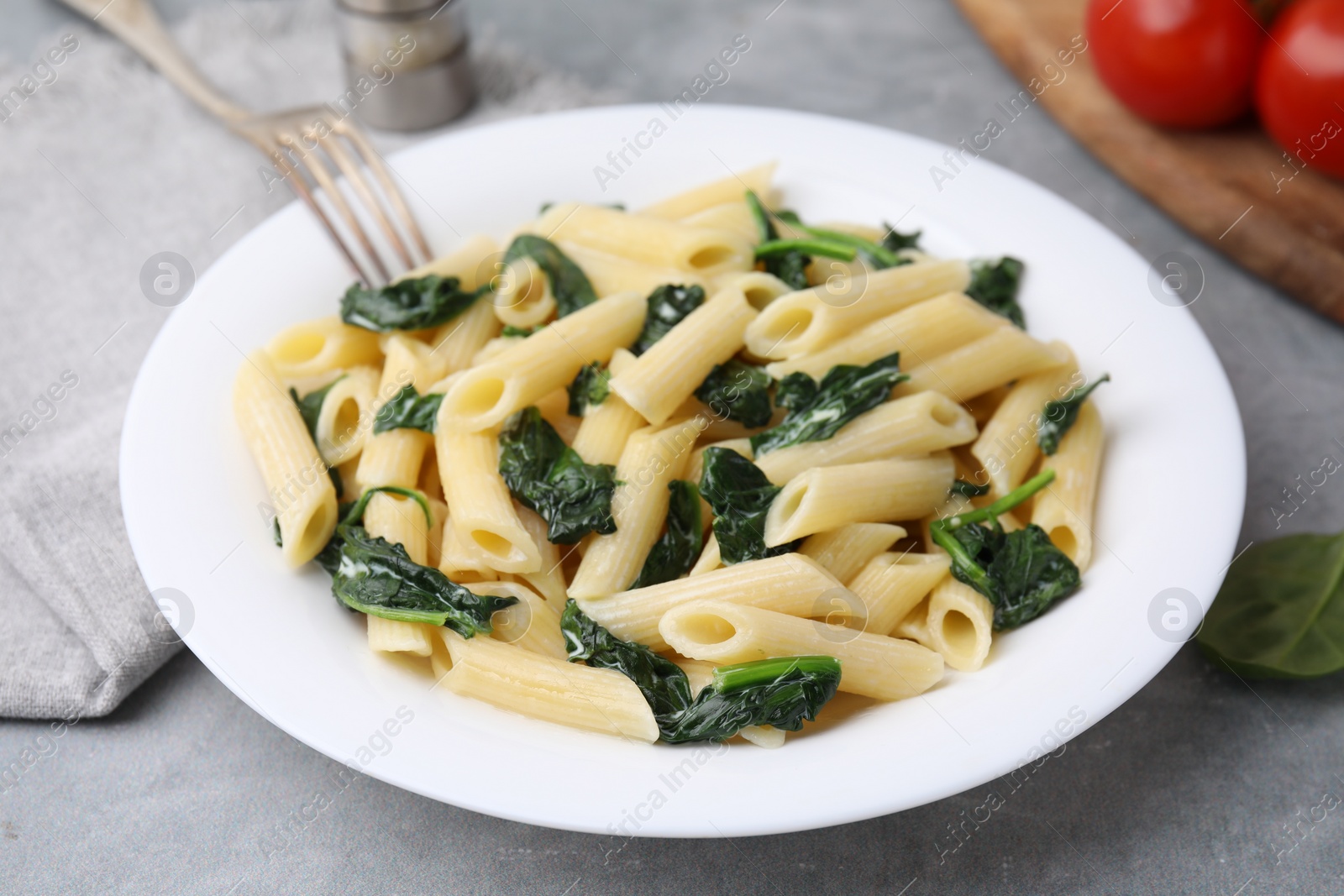 Photo of Tasty pasta with spinach on grey table, closeup