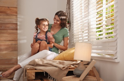 Happy mother with little daughter near window at home