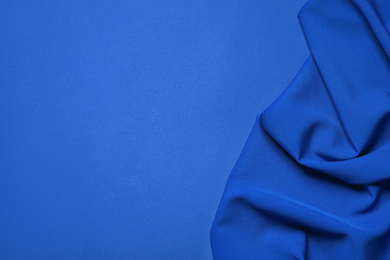 Photo of Crumpled fabric and space for text on bright background, top view. Color of the year 2020 (Classic blue)