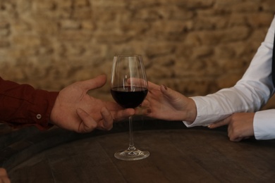 Photo of Waitress serving glass of red wine to client in restaurant, closeup