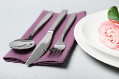 Photo of Cutlery and napkin on grey table, closeup. Festive table setting