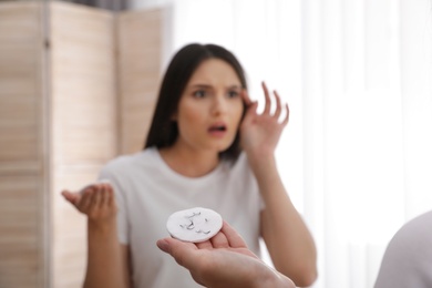 Photo of Beautiful woman holding cotton pad with fallen eyelashes near mirror indoors