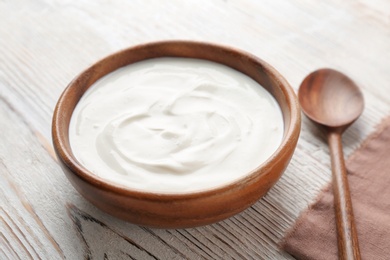 Bowl with tasty yogurt on wooden table