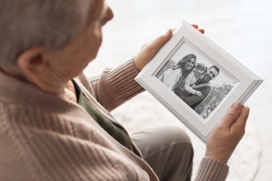 Elderly woman with framed family portrait at home
