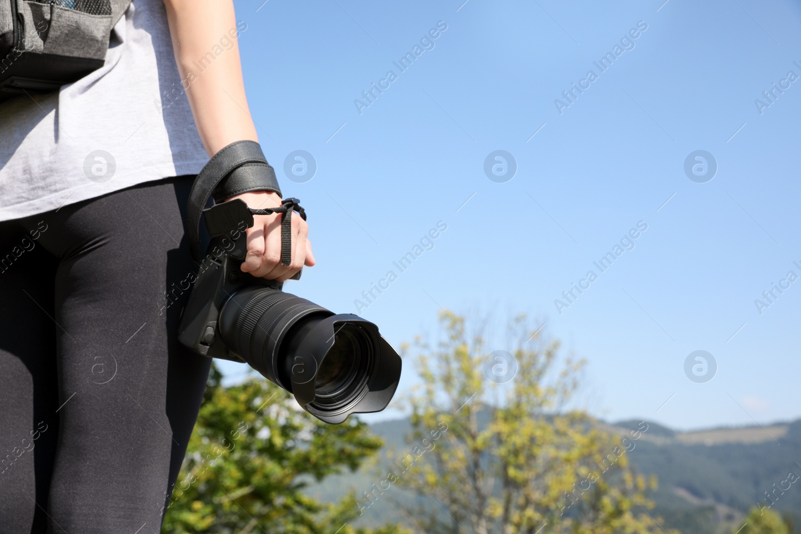 Photo of Professional photographer with modern camera in mountains, closeup. Space for text