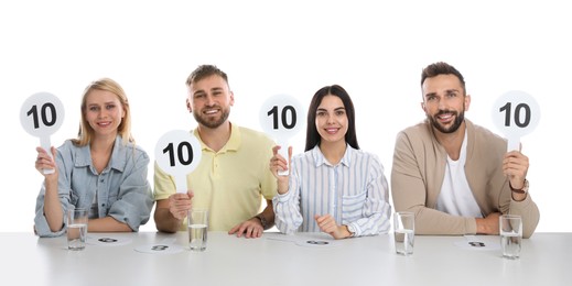 Photo of Panel of judges holding signs with highest score at table on white background