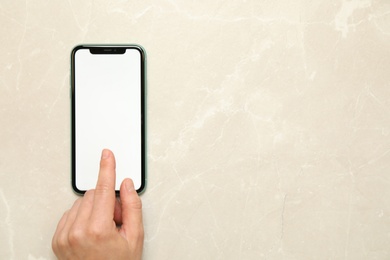 Photo of MYKOLAIV, UKRAINE - JULY 07, 2020: Woman using iPhone 11 on light grey marble background, top view. Mockup for design