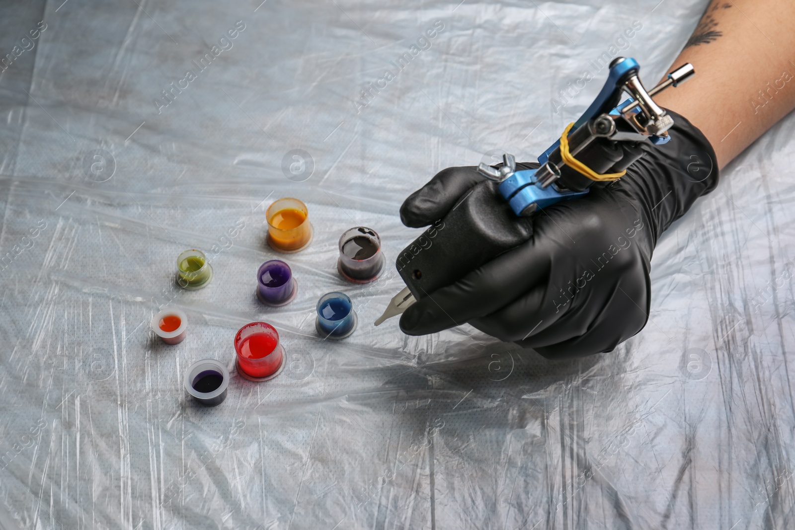 Photo of Tattoo artist with machine and inks at table, closeup