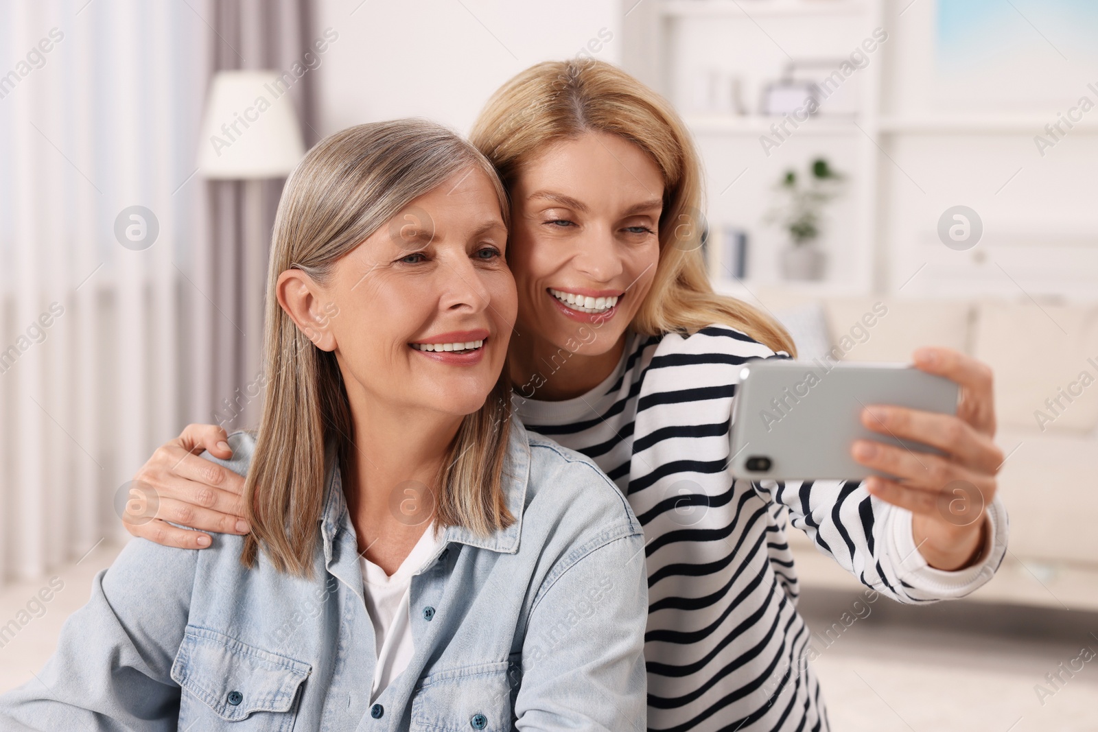 Photo of Happy mature mother and her daughter taking selfie at home