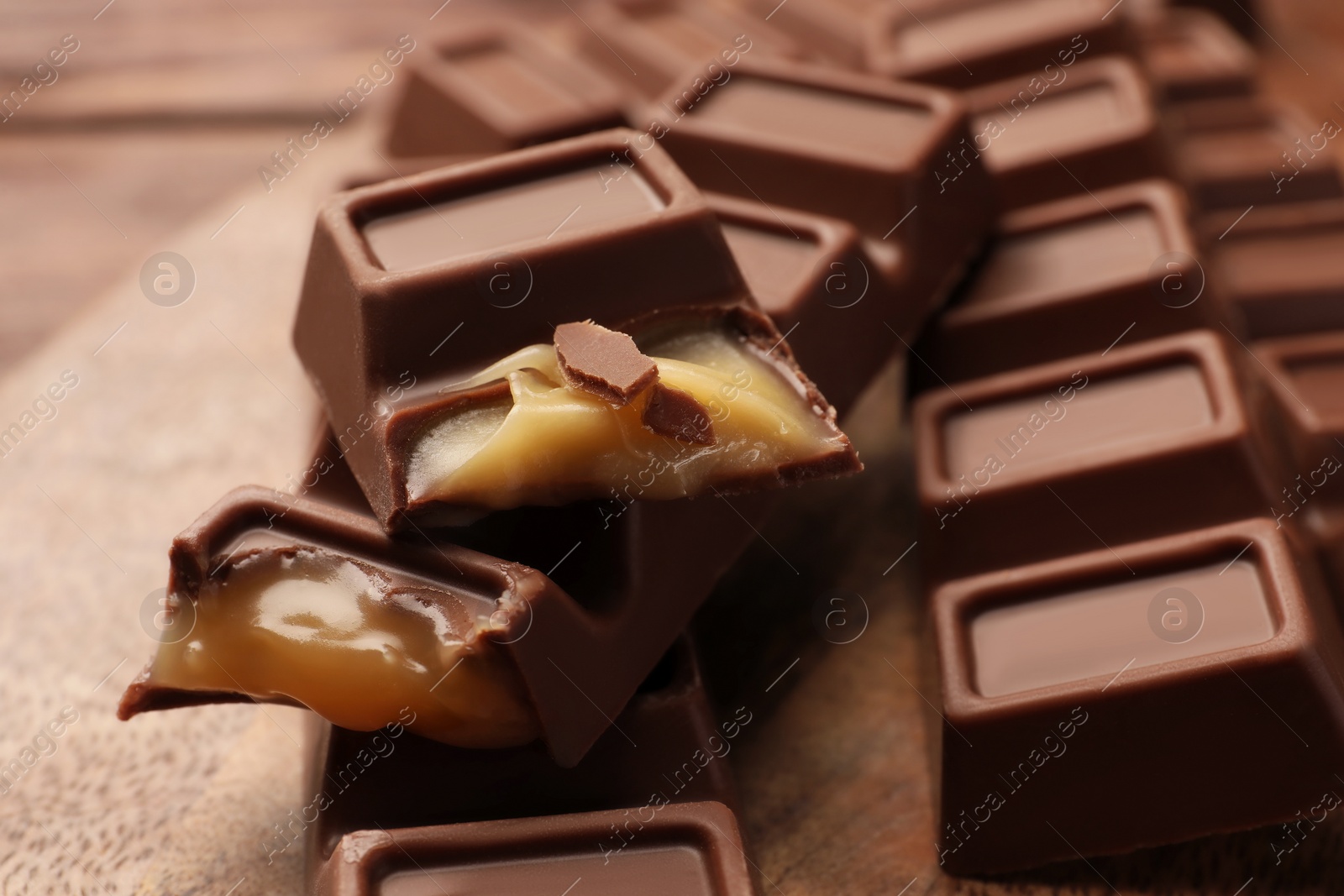 Photo of Tasty chocolate bars on wooden board, closeup