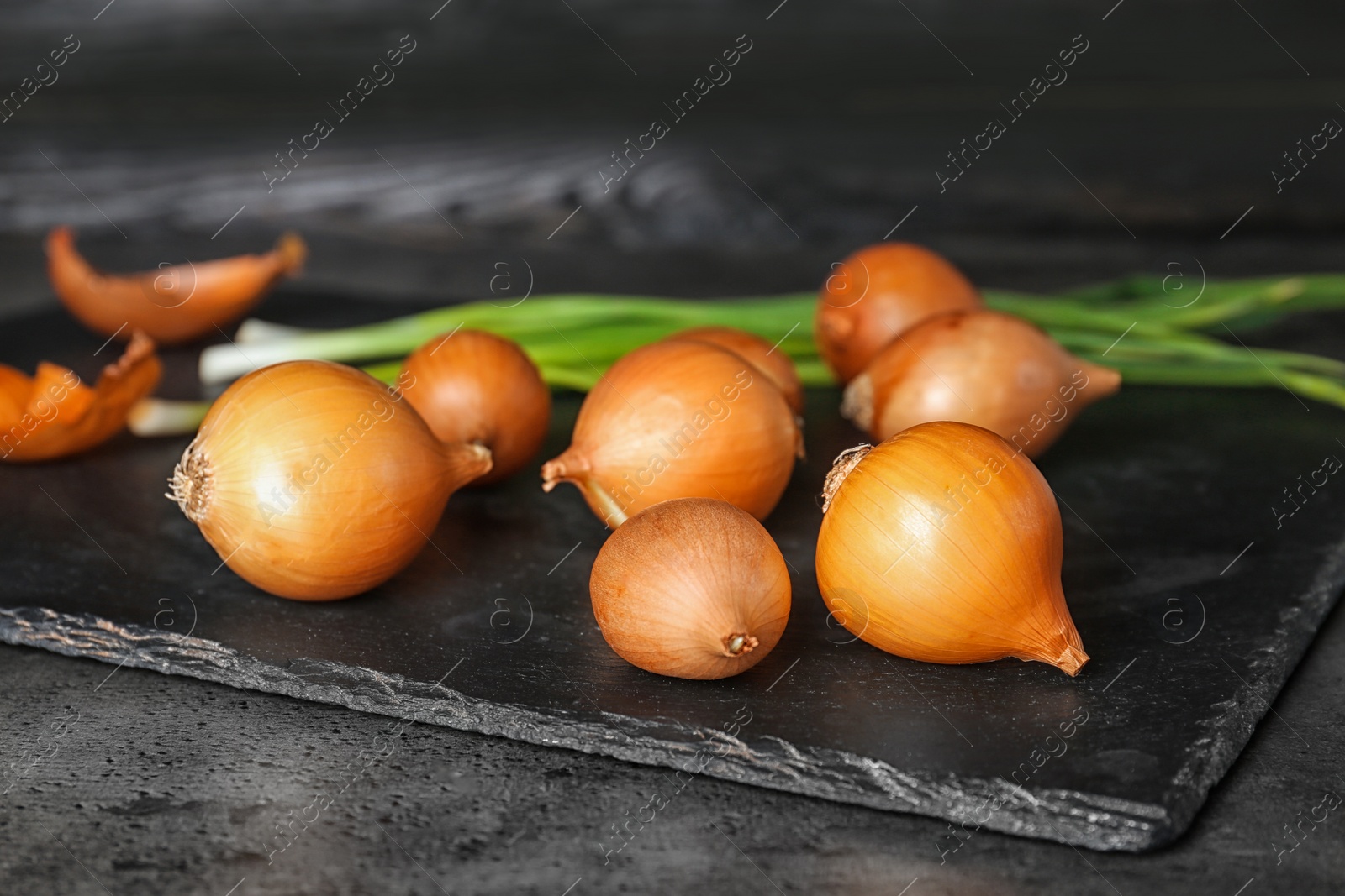 Photo of Slate plate with fresh ripe onions on table