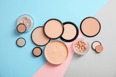 Flat lay composition with various makeup face powders on color background