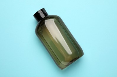 Photo of Bottle of shampoo on light blue background, top view