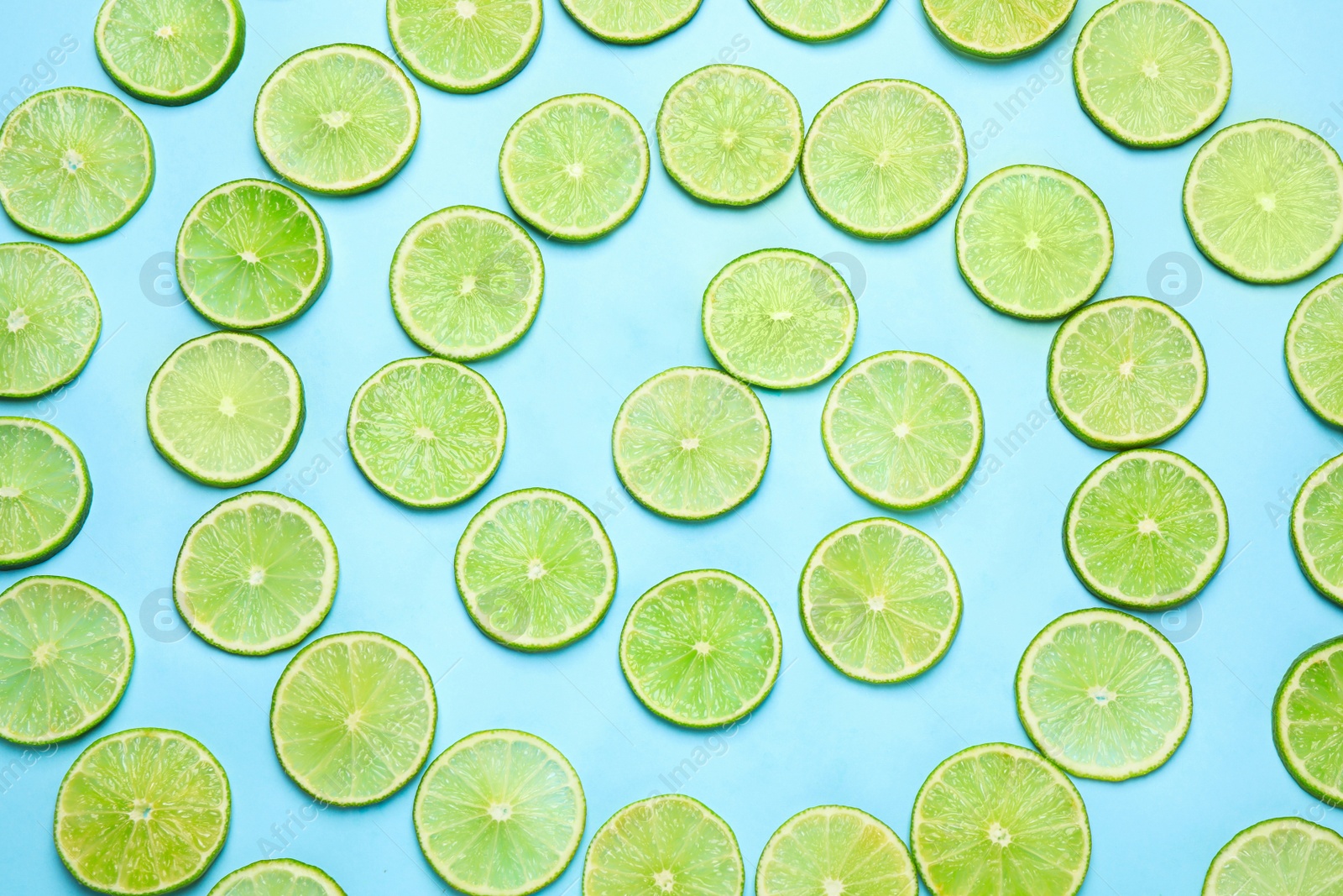 Photo of Juicy fresh lime slices on light blue background, flat lay