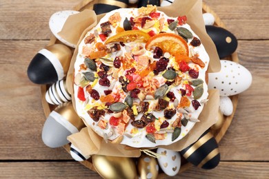 Photo of Traditional Easter cake with dried fruits and painted eggs on wooden table, top view