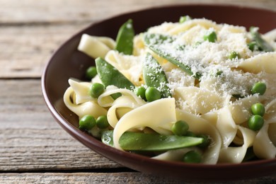 Delicious pasta with green peas and cheese on wooden table