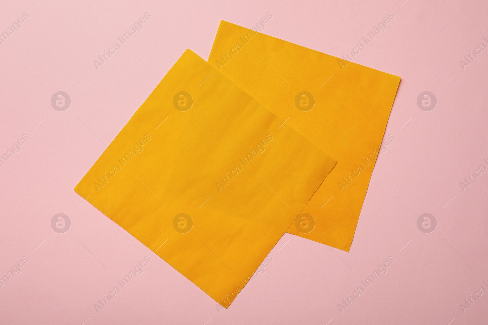 Photo of Orange reusable beeswax food wraps on pink background, top view