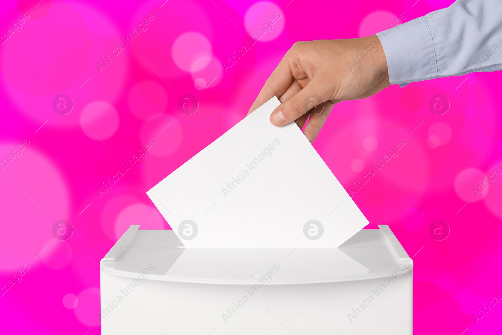 Image of Man putting his vote into ballot box on pink background, closeup