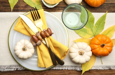 Seasonal table setting with pumpkins and other autumn decor on wooden background, flat lay