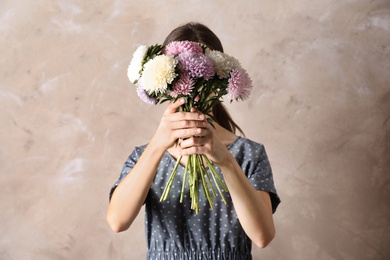 Photo of Woman holding beautiful aster flower bouquet against color background