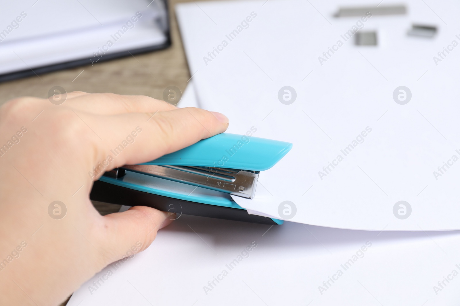 Photo of Woman stapling papers at table, closeup view