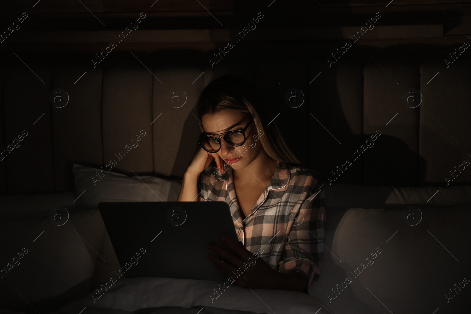 Photo of Young woman using laptop in bed at night. Sleeping disorder problem